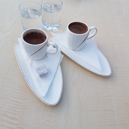 Yaprak desenli tabaklarda Türk kahvesi servisi; yanında su ve lokum